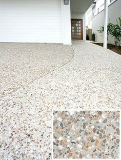 a house with white garage doors and gravel driveway in the foreground, two plants on either side of the front door