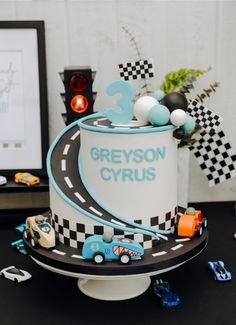 a birthday cake is decorated with cars and race track numbers on the top, as well as an image of a racing car