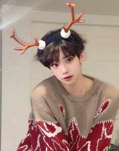 a young man with reindeer antlers on his head wearing a red and white sweater