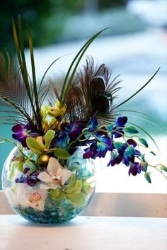 a vase filled with flowers and feathers on top of a table