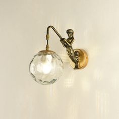 a wall light with a glass ball hanging from it's side