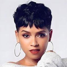 a woman with short black hair wearing large hoop earrings and a white top is posing for the camera