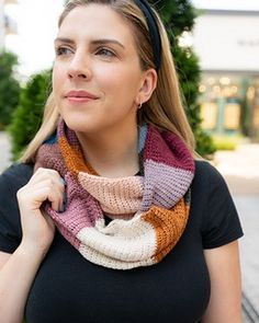 a woman wearing a black shirt and a multicolored knitted scarf on her neck