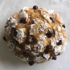 a cookie with chocolate chips and powdered sugar on it sitting on a white surface