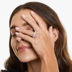 a woman holding her hands to her face with one hand and the other eye closed