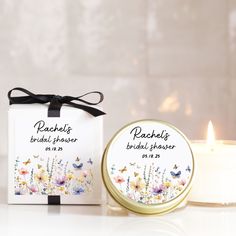 a white candle next to a small box with a label on it that says peachelop bridal shower