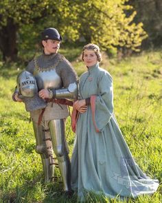 a man and woman dressed up in medieval costumes standing next to each other on the grass