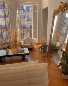 a living room filled with white furniture and lots of windows next to a wooden floor