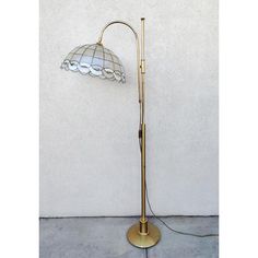 a lamp that is on top of a floor next to a wall with a white background