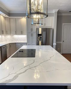 a large kitchen with marble counter tops and stainless steel appliances in the center, along with a chandelier hanging from the ceiling