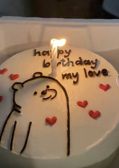 a birthday cake with the words happy birthday my love written on it and a lit candle in the shape of a bear