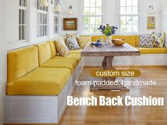 a yellow couch sitting under a window next to a wooden table