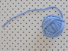 a ball of blue yarn sitting on top of a polka dot tablecloth covered with dots