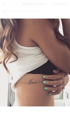 a woman's stomach with the word love tattooed on her lower body and green nail polish