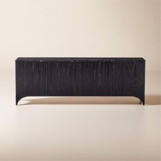 a black wooden bench sitting on top of a white floor next to a beige wall