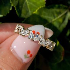 a woman's hand holding a gold ring with five diamonds on the top and bottom