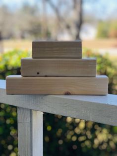 three pieces of wood are stacked on top of each other in front of some bushes