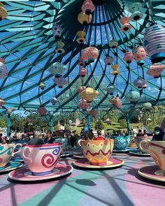 colorful tea cups and saucers are on display under a glass roof