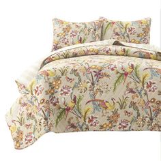 the comforter is made up with colorful flowers and birds on it's bed