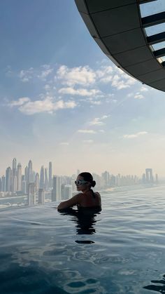 a woman in a swimming pool with the cityscape in the backgroud