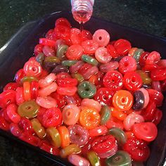 a tray filled with lots of different colored donuts on top of a counter next to a glass bottle