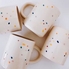 four coffee mugs stacked on top of each other with confetti printed on them