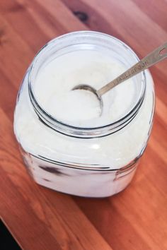 a glass jar filled with yogurt sitting on top of a wooden table