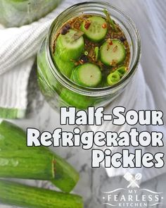 a jar filled with pickles sitting on top of a table next to cucumbers