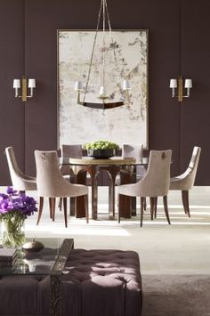 a dining room table with chairs and a bench in front of an art work on the wall