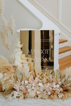 a book sitting on top of a table next to some flowers and plants in front of a stair case