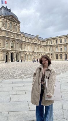 a woman standing in front of a large building