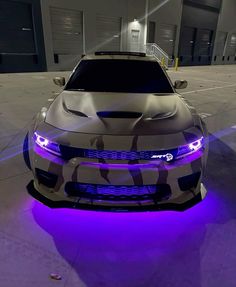 the front end of a car with purple lights on it's headlight and hood