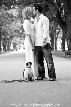 a man and woman standing next to each other with a dog in front of them