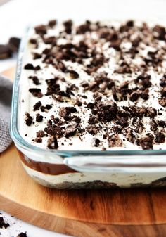 a glass dish filled with cookies and cream on top of a wooden cutting board next to an oven mitt