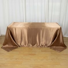 a table covered with a brown cloth on top of a hard wood floor