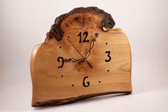 a clock made out of wood with numbers on the face and hands, sitting in front of a white background