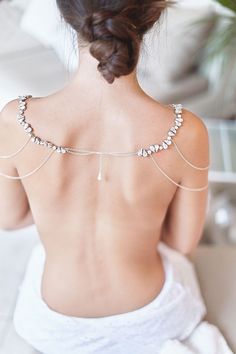 the back of a woman's body wearing a white towel and silver chain necklace