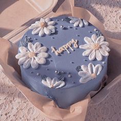 there is a blue cake with white flowers on it and the words happy written in frosting