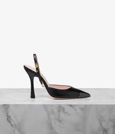 a pair of black high heeled shoes on top of a marble slab with gold accents