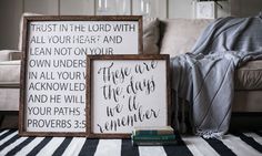 two framed signs sitting on top of a black and white striped rug next to a couch