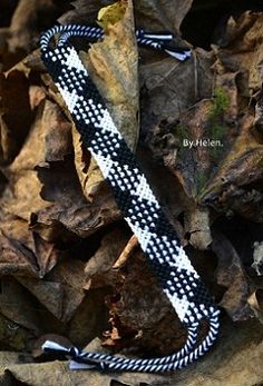 a black and white bracelet laying on top of some leaf covered ground next to rocks