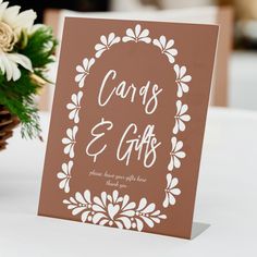 a card with the words cards and gifts on it sitting next to a bouquet of flowers