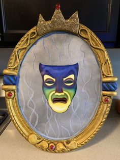 a mirror with a painting of a man's face in the center and a crown on top