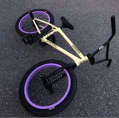 an upside down bike with purple rims on the pavement