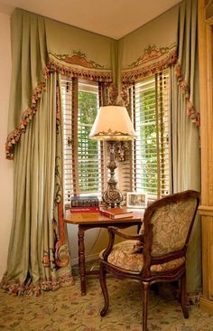 a chair and lamp in front of a window with curtains on the windowsills