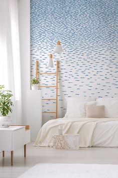 a white bed sitting under a blue and white wall