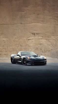 a black sports car parked in front of a mountain