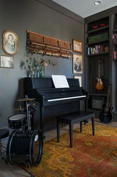 a living room with a piano, drums and bookshelf in it's corner