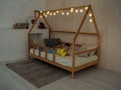 a little boy laying on top of a bed with lights strung from the ceiling above him