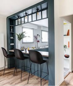 a kitchen with blue walls and white counter tops next to a dining room table that has black chairs on it